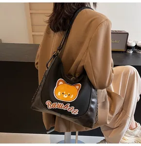 Détail du sac cabas noir avec broderie d'ours jaune et bandoulière en chaîne métal