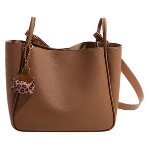 Brown litchi leather tote bag with bucket design and leopard print mini pouch charm