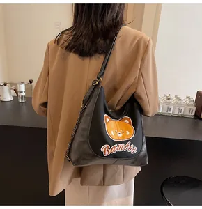 Détail de la broderie ours et bandoulière en chaîne sur le sac cabas noir