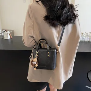 Sac seau noir moderne avec breloque en peluche et bandoulière porté par un mannequin
