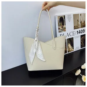 Détail du sac cabas beige grainé avec un foulard en soie élégant enroulé sur la poignée