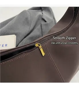 Detailansicht des goldenen Reißverschlusses und der Nähte an brauner Ledertasche