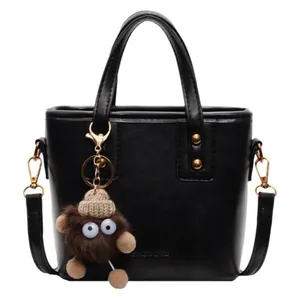 Sac seau en cuir noir avec poignée, bandoulière amovible et pendentif monstre en peluche