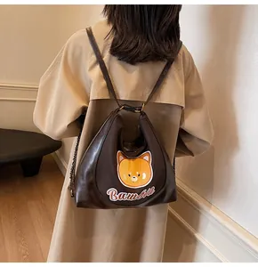 Détail du sac à dos en cuir marron avec broderie ours jaune et lettrage Bawall