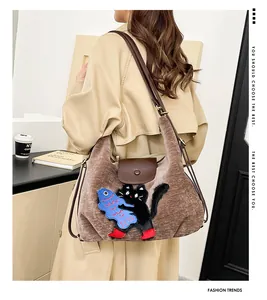 Détail du sac cabas en velours marron avec broderie chat et bandoulière en cuir ajustable