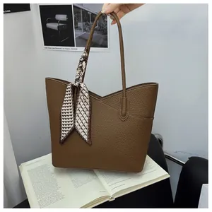 Gros plan d'un sac cabas marron motif litchi avec foulard en soie et poche en V