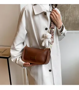 Detail of dark brown Boston bag with leopard print strap and white plush bear charm