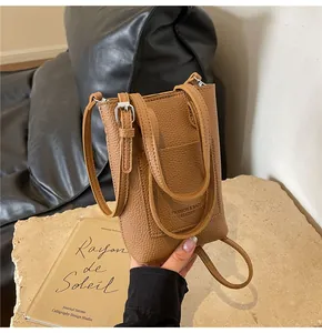 Détail du mini sac de téléphone en cuir grainé fauve avec logo gaufré et sangle réglable