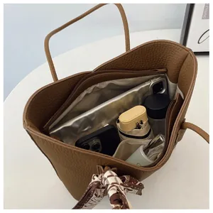 Vue intérieure du cabas marron avec poche zippée contenant une tablette et objets