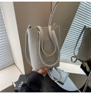 Détail d'un mini sac seau en cuir grainé gris clair avec deux petites poignées