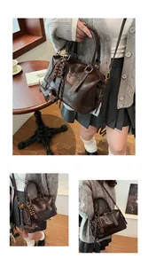 Detail view of chocolate brown boston bag with fun charms and polished leather finish