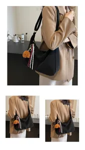 Detail der schwarzen Hobo-Tasche mit großem Fassungsvermögen und Teddybär-Anhänger