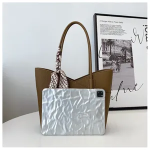 Détail du sac cabas en cuir marron avec foulard décoratif et référence de taille