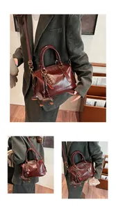 Detail of burgundy Boston bag with chocolate and dachshund pendants in a lifestyle shot