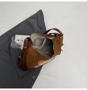 Détail de broderie d'ours sur sac à bandoulière marron avec poche intérieure zippée