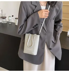 Close-up of a light grey textured leather mini crossbody bag with fashion logo detail