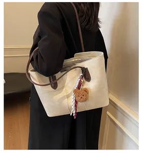 Close-up of minimalist cream tote bag with brown straps and cute bear charm decoration