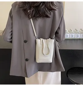 Vertical mini crossbody phone bag in cream lychee leather shown on a shoulder