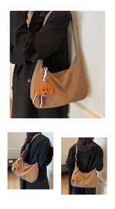 Detail der hellbraunen Halbmond-Tasche mit einem süßen Teddybär-Plüsch-Anhänger