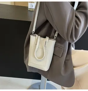 Detail view of beige lychee pattern leather mini crossbody bag with embossed logo