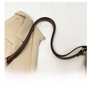 Détail de la bandoulière en cuir marron foncé avec boucle dorée et coutures fines