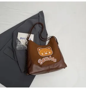 Détail du sac cabas marron vintage avec broderie d'ours et bandoulière chaîne en métal