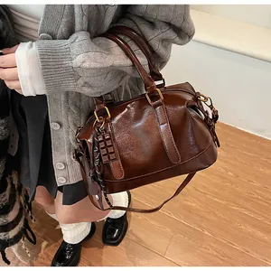 Detail of glossy chocolate brown Boston bag with shoulder strap and chocolate charm