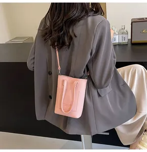 Detailed view of mini pink textured leather crossbody bag with top handles and strap