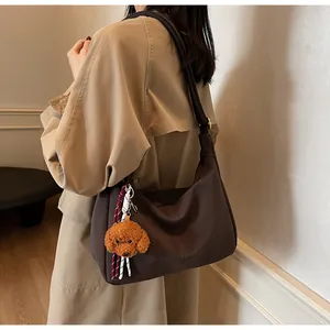 Detaillierte Seitenansicht der kaffeebraunen Hobo-Tasche mit Teddy-Anhänger