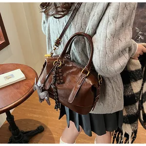 Detail of dark brown leather boston bag with decorative dog and chocolate charms
