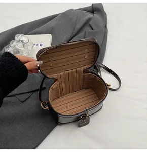 Detail of deep brown cylinder bag showing striped fabric lining and dual metal zippers