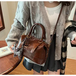 Deep brown Boston bag detail with round handles and decorative charms on model