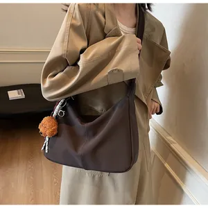 Dunkelbraune Hobo-Tasche mit Bärenanhänger, getragen von einem Model im Wohnbereich