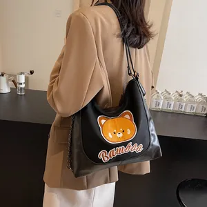Sac cabas tendance en toile noire avec broderie ours et chaîne porté par un mannequin
