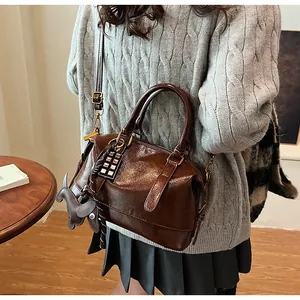 Detail of vintage dark brown faux leather bag with dog charm and woven strap detail