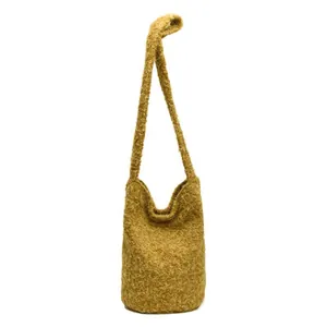 Minimalist mustard yellow soft knit bucket bag with long shoulder strap on white background