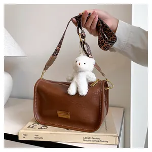 Retro brown cylinder bag detail with leopard strap and plush bear charm accent
