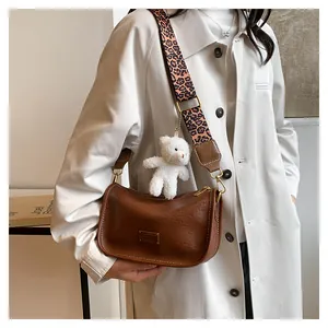 Brown Boston crossbody bag with leopard print strap and plush bear charm on model
