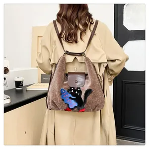 Gros plan du sac à dos en peluche marron avec broderie chat et détails en cuir