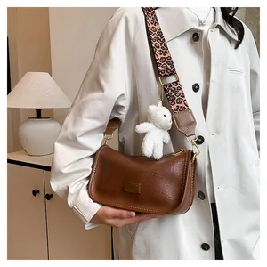 Detail of brown litchi pattern leather bag with leopard strap and plush bear charm