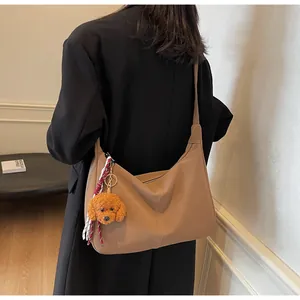 Detailansicht einer braunen Leder-Tote-Bag mit Plüschanhänger und gestreiftem Schleifenakzent