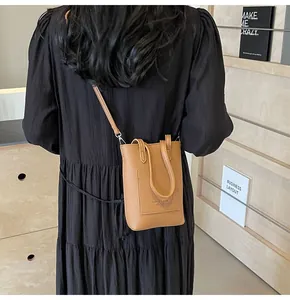 Detail of tan pebble leather mini crossbody bag shown on a black dress backdrop
