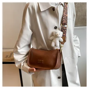 Brown leather Boston bag with leopard print strap and plush bear charm on a model
