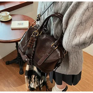 Brown high-gloss Boston bag with chocolate pendant on a wooden cafe table scene