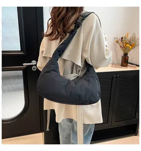 Modèle portant un sac demi-lune noir en nylon matelassé avec bandoulière réglable