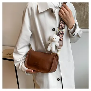 Detail of retro brown leather Boston bag with leopard print strap and bear charm