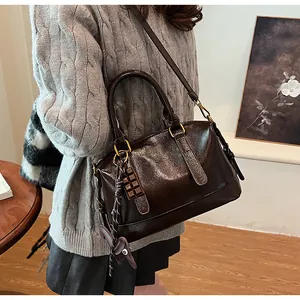 Macro detail of dark brown glossy retro pillow bag with cute charms and shoulder strap