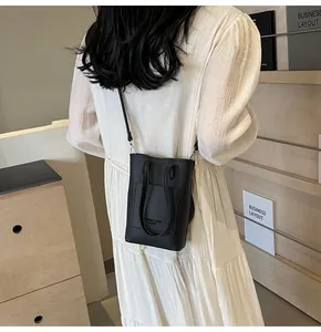 Rear view of model wearing a black litchi pattern mini bucket bag with a slim strap