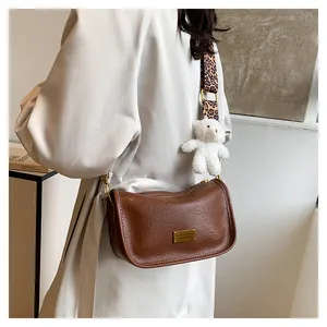 Brown vintage Boston crossbody bag with leopard print strap and plush bear charm