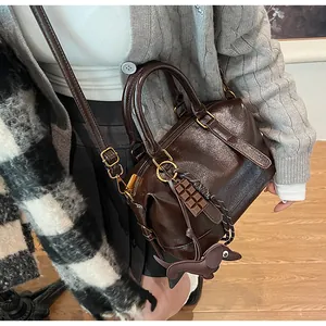 Detail of vintage dark brown Boston bag with chocolate and puppy charms on a crossbody strap